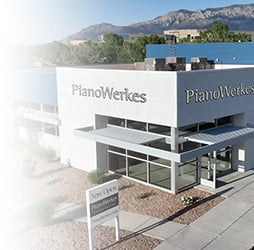 PianoWerke store exterior with mountains in the background and a Now Open sign.