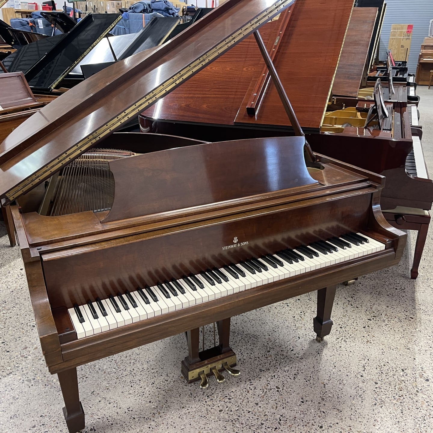 Grand piano in a showroom with a polished wooden finish, highlighting keys and pedals. Ideal for music lovers.