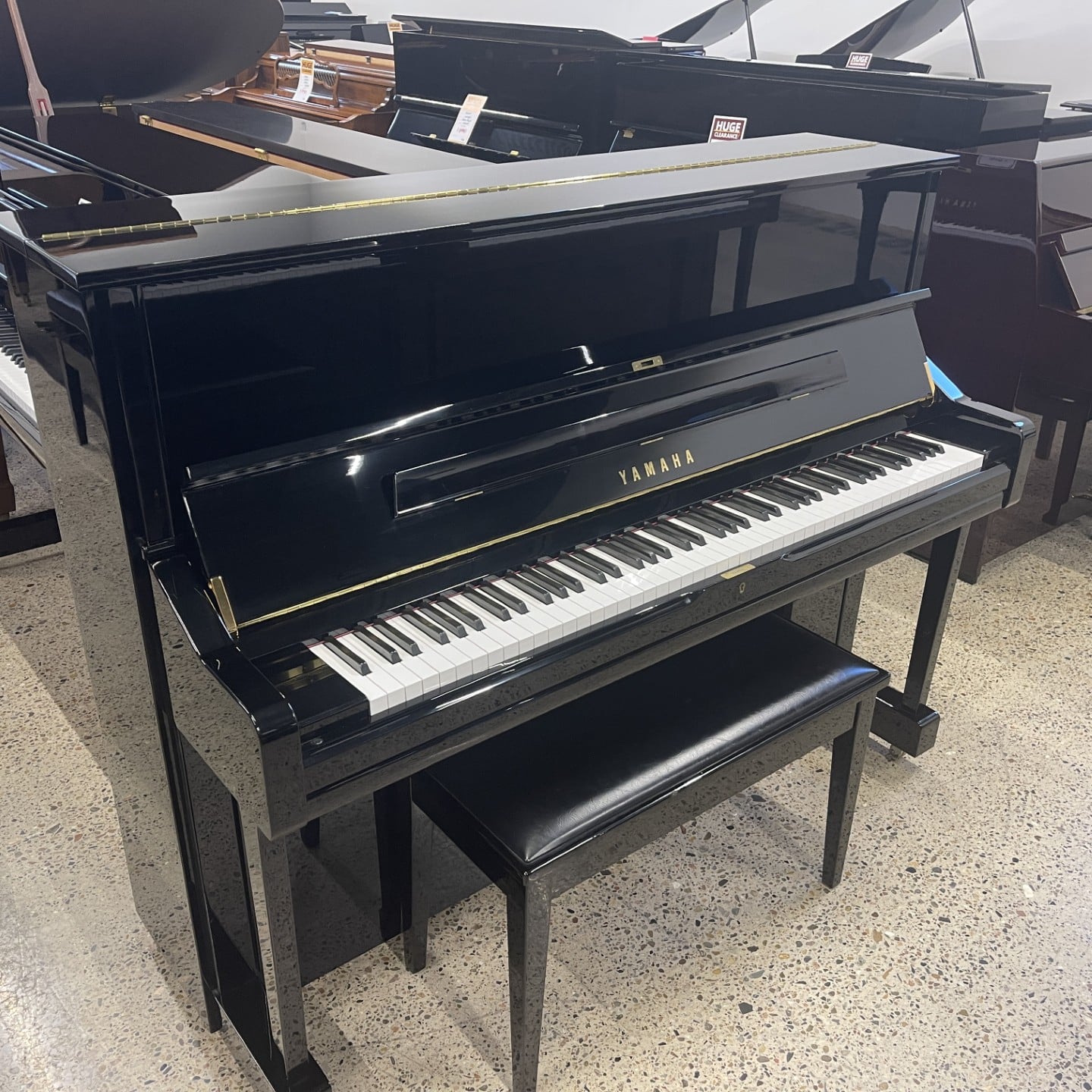Black upright Yamaha piano with matching bench in a showroom.