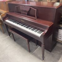 Classic Baldwin upright piano with mahogany finish and matching bench on display in a showroom.
