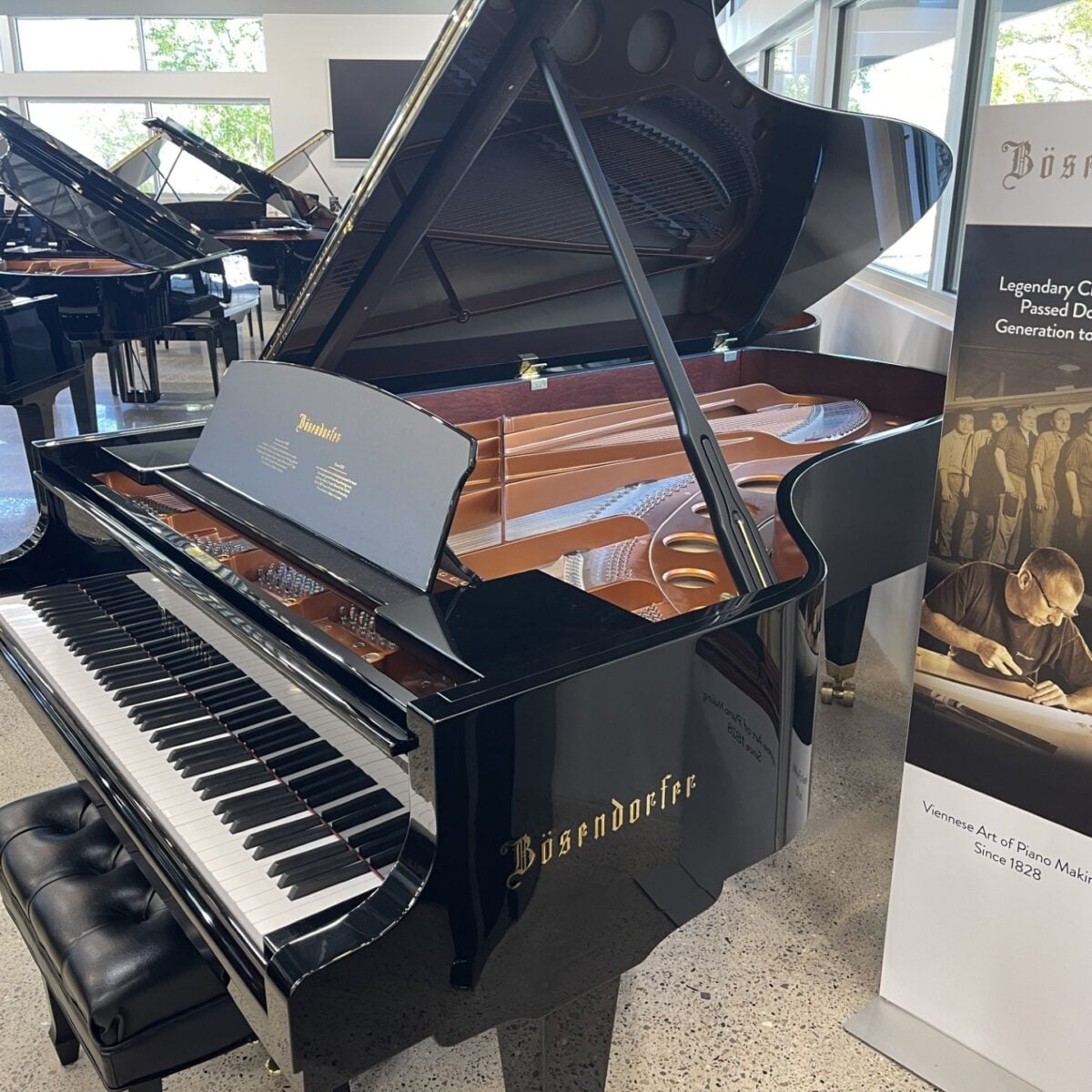Bösendorfer grand piano displayed in a showroom with an open lid, showcasing its intricate craftsmanship.