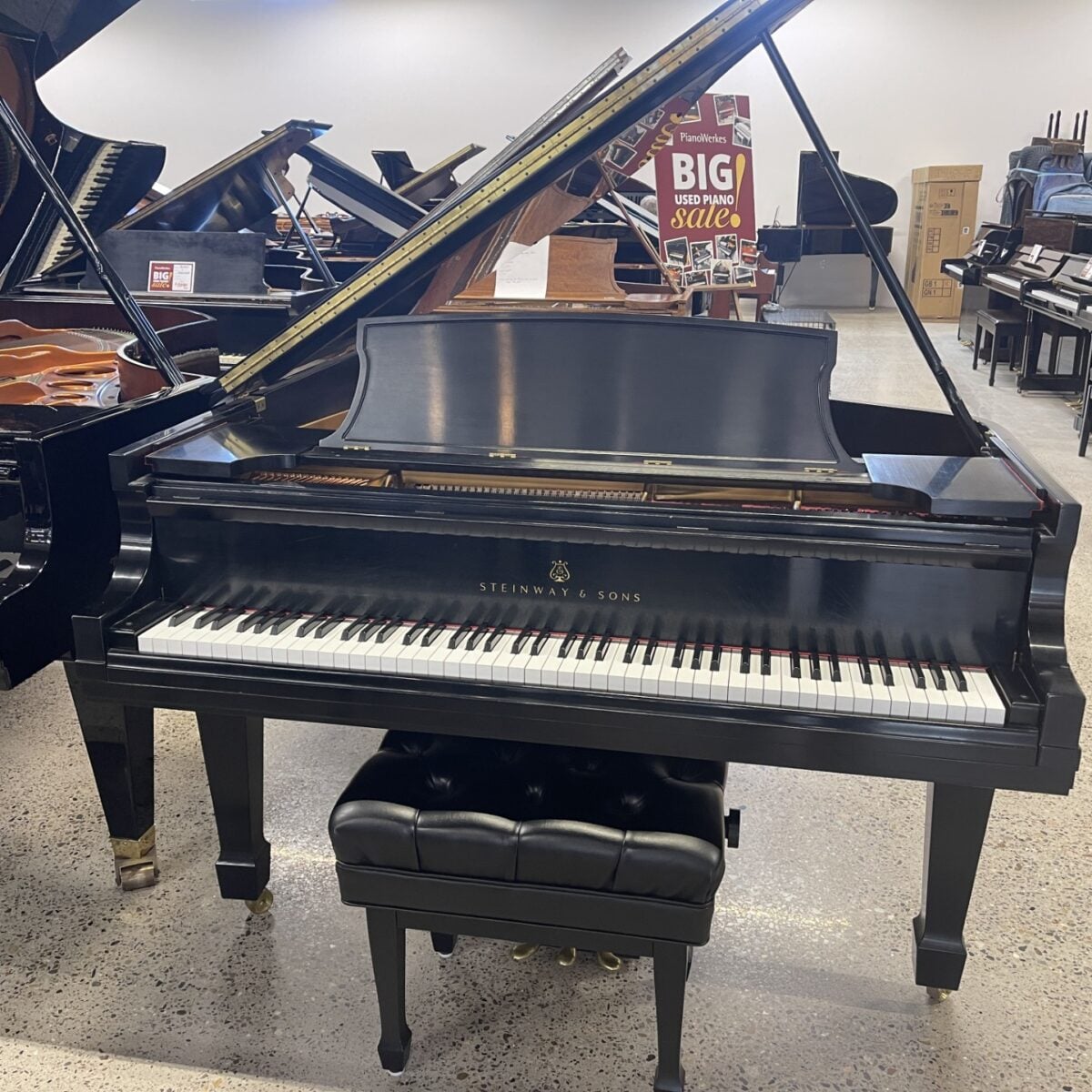 A Steinway & Sons grand piano on showroom display for a used piano sale event.