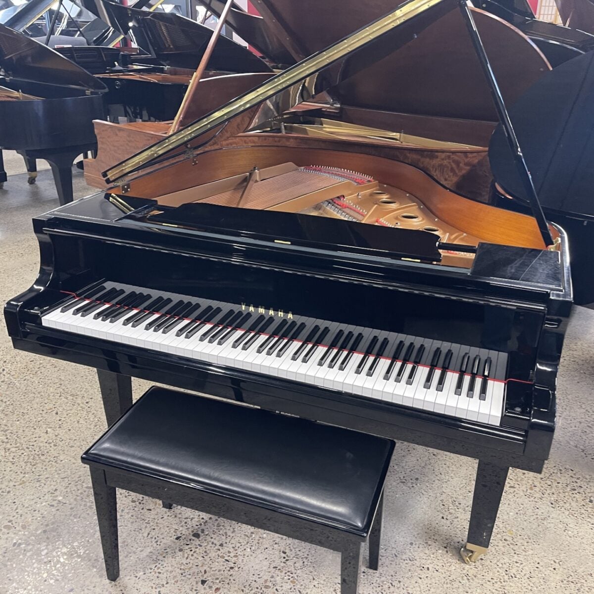Grand piano with open lid and bench in a showroom. Perfect for elegant performances and music events.