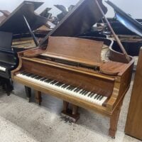 Elegant grand piano with open lid, showcasing a classic design and polished wood finish in a showroom setting.