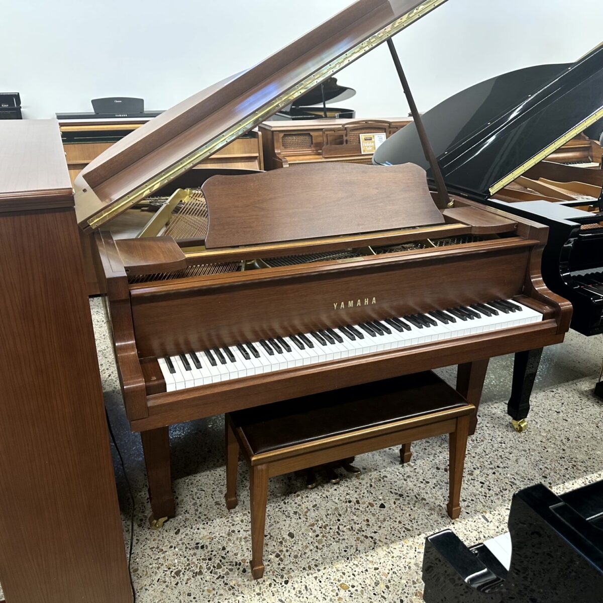 Wooden Yamaha grand piano with open lid, showcasing a classic design and ivory keys in a showroom.