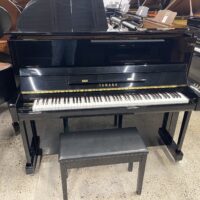 Black Yamaha upright piano with matching bench on showroom floor.