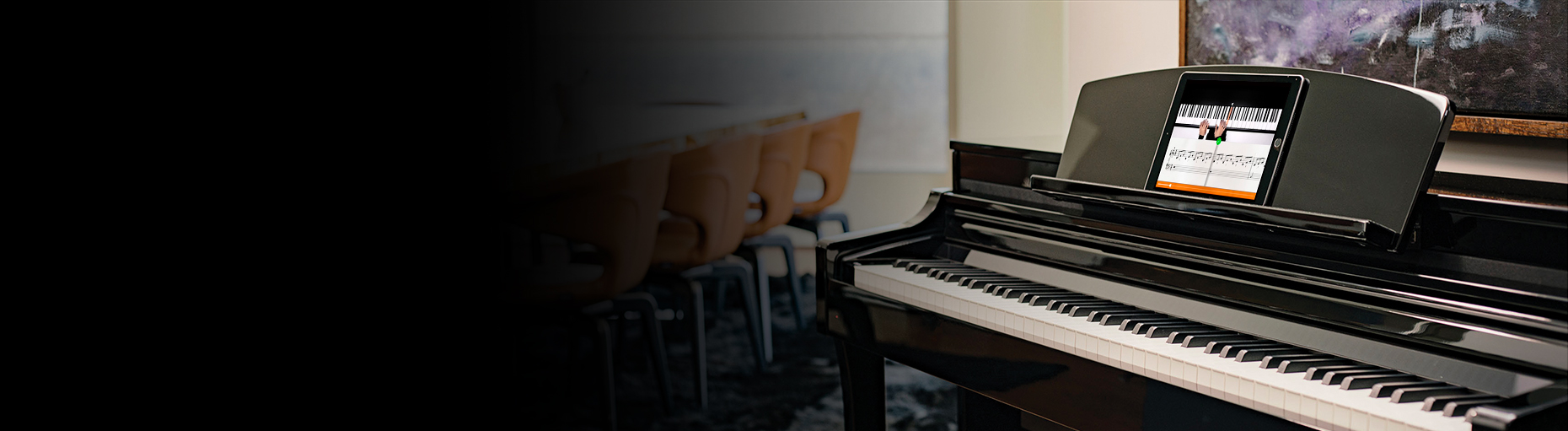 Digital piano with a tablet displaying sheet music, situated in a modern room with a conference table in the background.
