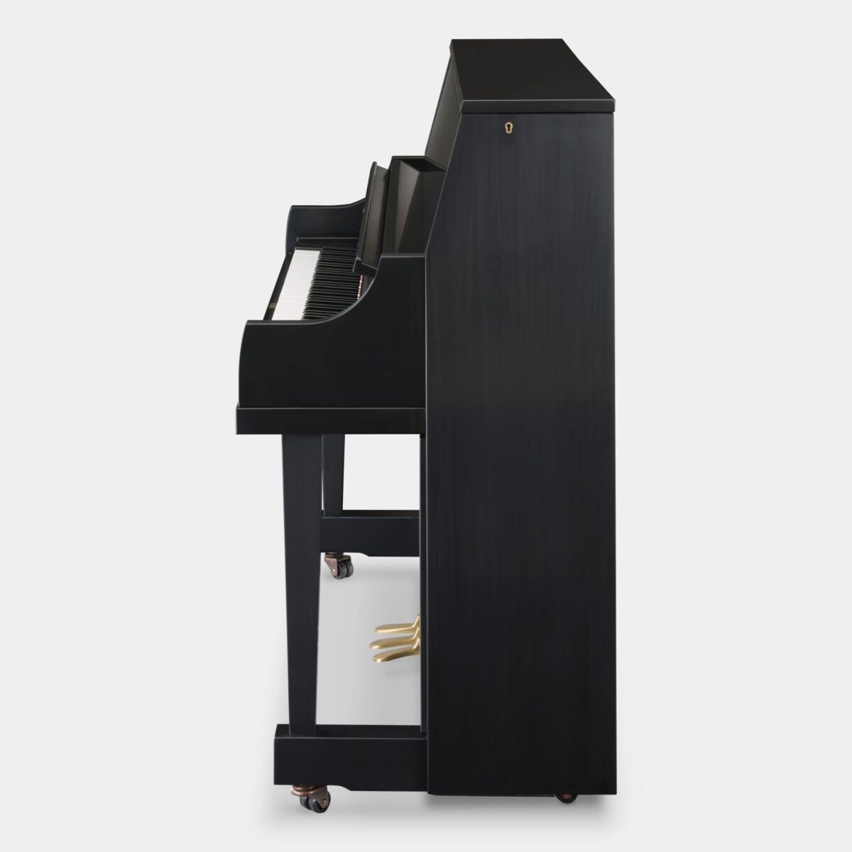 Side view of a black upright piano with brass pedals on a white background.