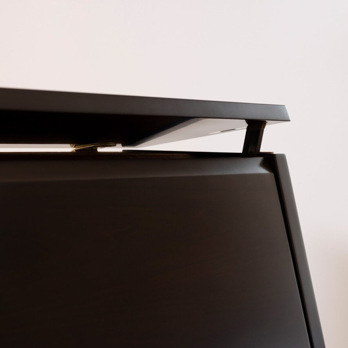 Close-up of a modern, sleek black piano lid slightly open, showcasing its elegant design against a neutral background.