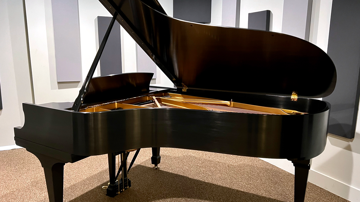 Steinway-grand-piano-from-back Elegant black grand piano in a soundproof room, showcasing its intricate golden interior and polished finish.
