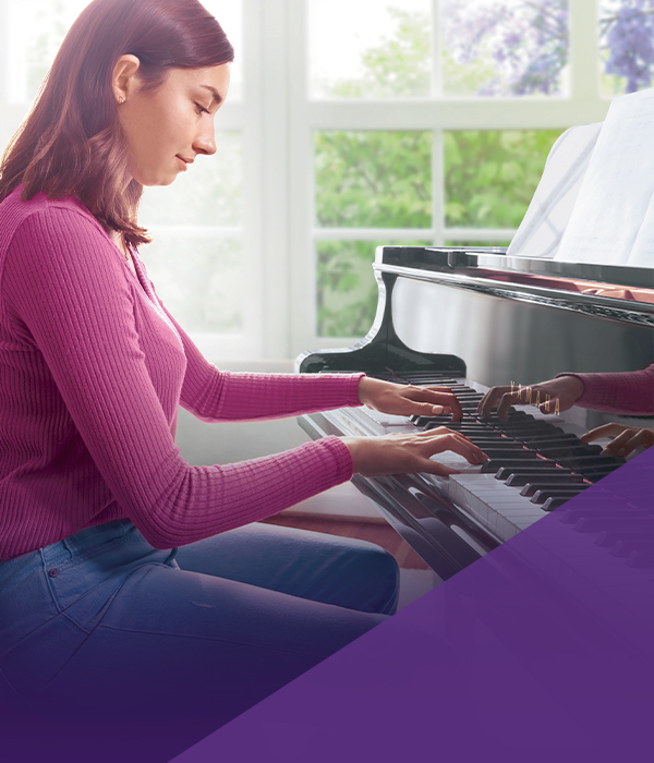 Young woman playing a polished grand piano, showcasing premium craftsmanship and rich sound quality at Piano Werks.