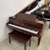 Alt text: K. Kawai polished mahogany grand piano with a matching bench, showcasing premium craftsmanship and rich sound quality.