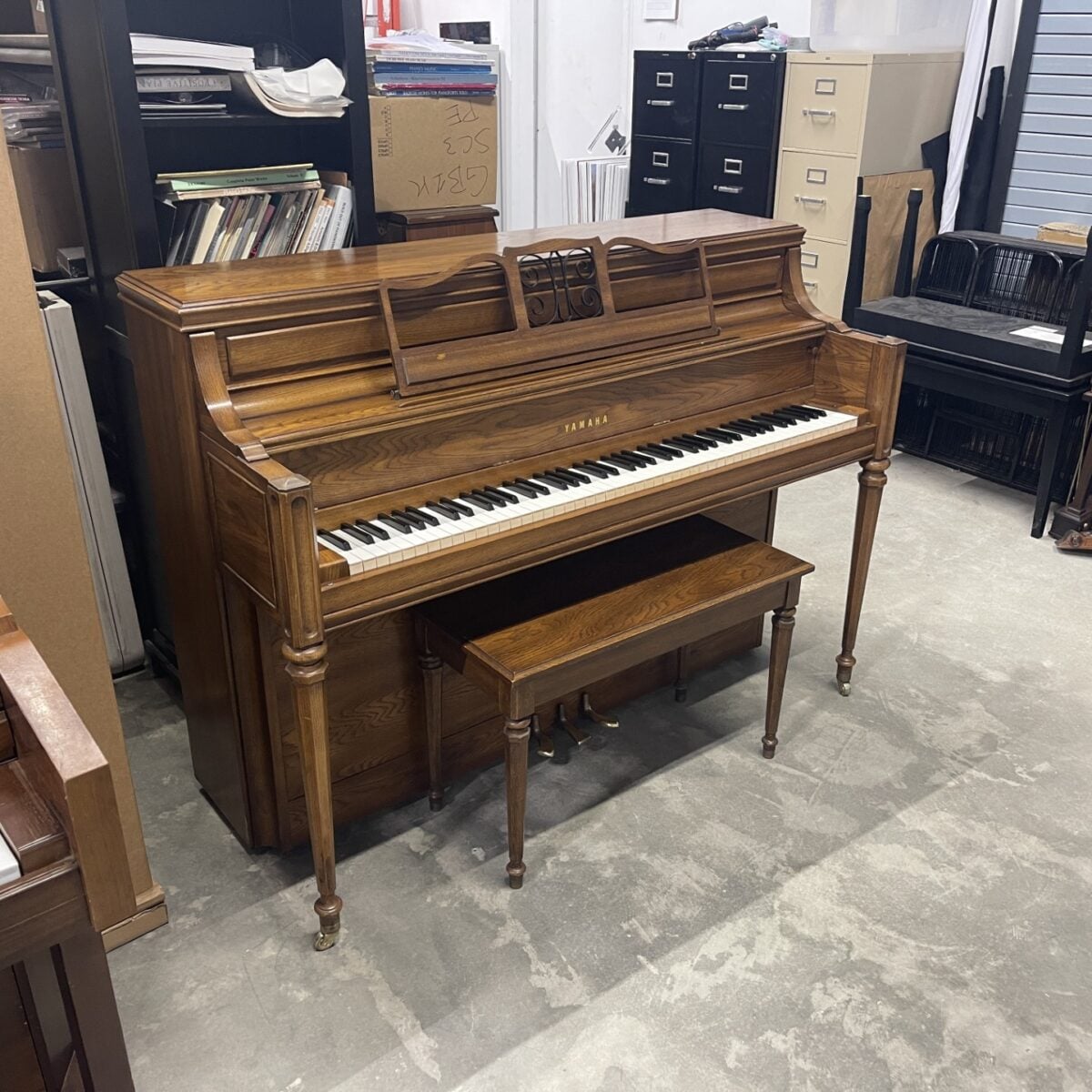 Alt text: Tuned Yamaha console piano with polished wood finish and matching bench, showcasing craftsmanship and quality.