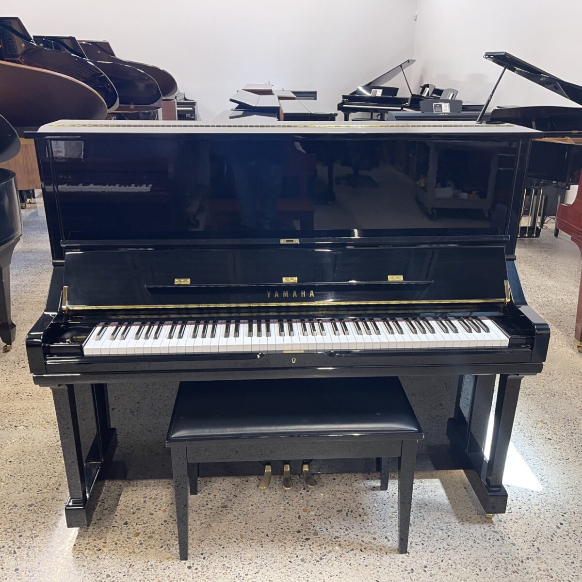 Yamaha upright piano in polished ebony finish, featuring a classic design and responsive touch for superior performance.