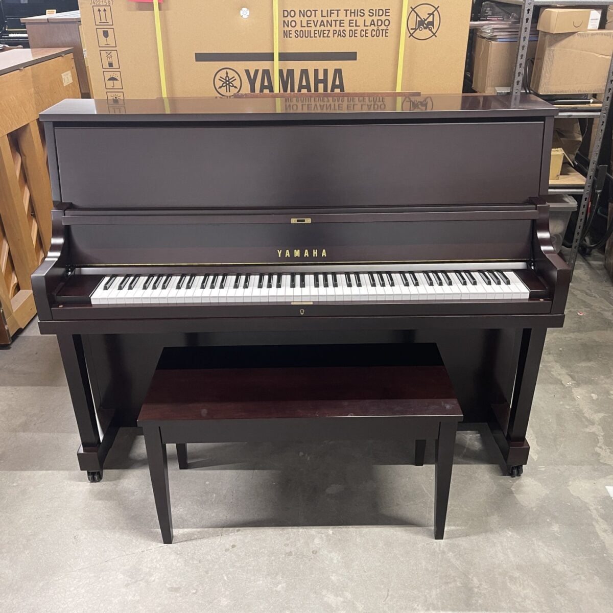 Yamaha upright piano in polished mahogany finish, complete with matching bench for comfortable practice and performance.
