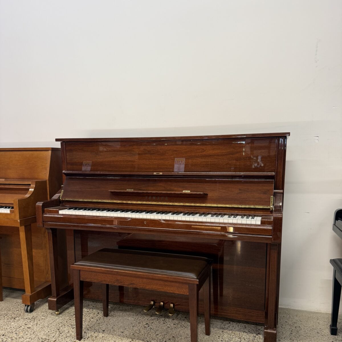 Classic upright piano in mahogany finish with elegant design, paired with a matching padded bench for comfort and style.