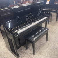 Yamaha upright piano with polished ebony finish and matching bench, showcasing quality craftsmanship and classic design.