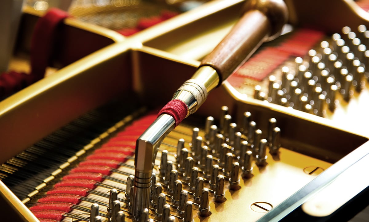 Close-up of piano tuning pins and tool, showcasing precision craftsmanship and quality materials in piano maintenance.