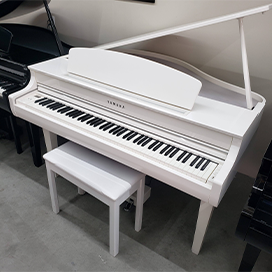 White grand piano with matching bench in a showroom setting. Ideal for elegant musical performances and home decor.