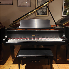 Grand piano with open lid in a warmly lit room, showcasing its elegant design and craftsmanship.