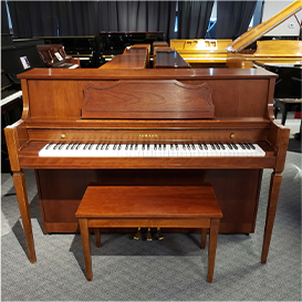 Upright brown piano with matching bench in a showroom setting. Perfect for home music practice or performance.